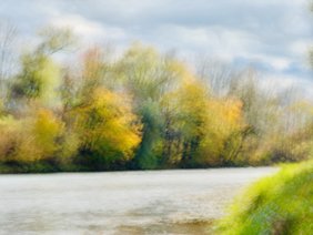 Verschwommener Blick auf buntgefärbte Herbstbäume und einen Fluss | ©Franz Bader