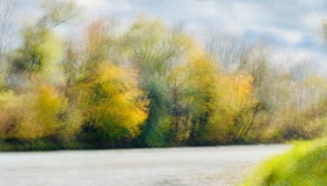 Verschwommener Blick auf buntgefärbte Herbstbäume und einen Fluss | ©Franz Bader